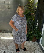 Woman in a patterned dress standing outdoors next to a plant