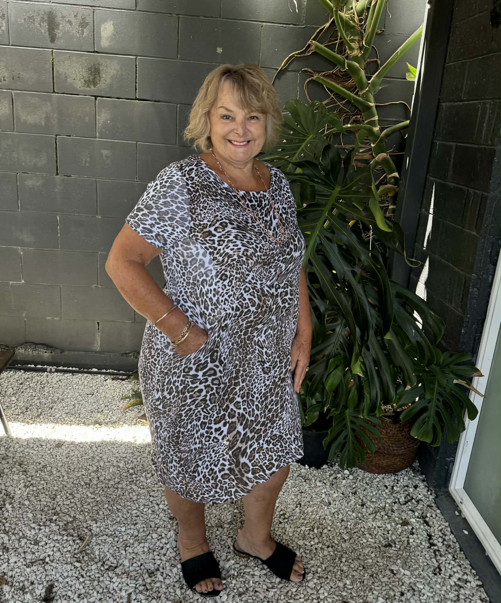 Woman in a patterned dress standing outdoors next to a plant