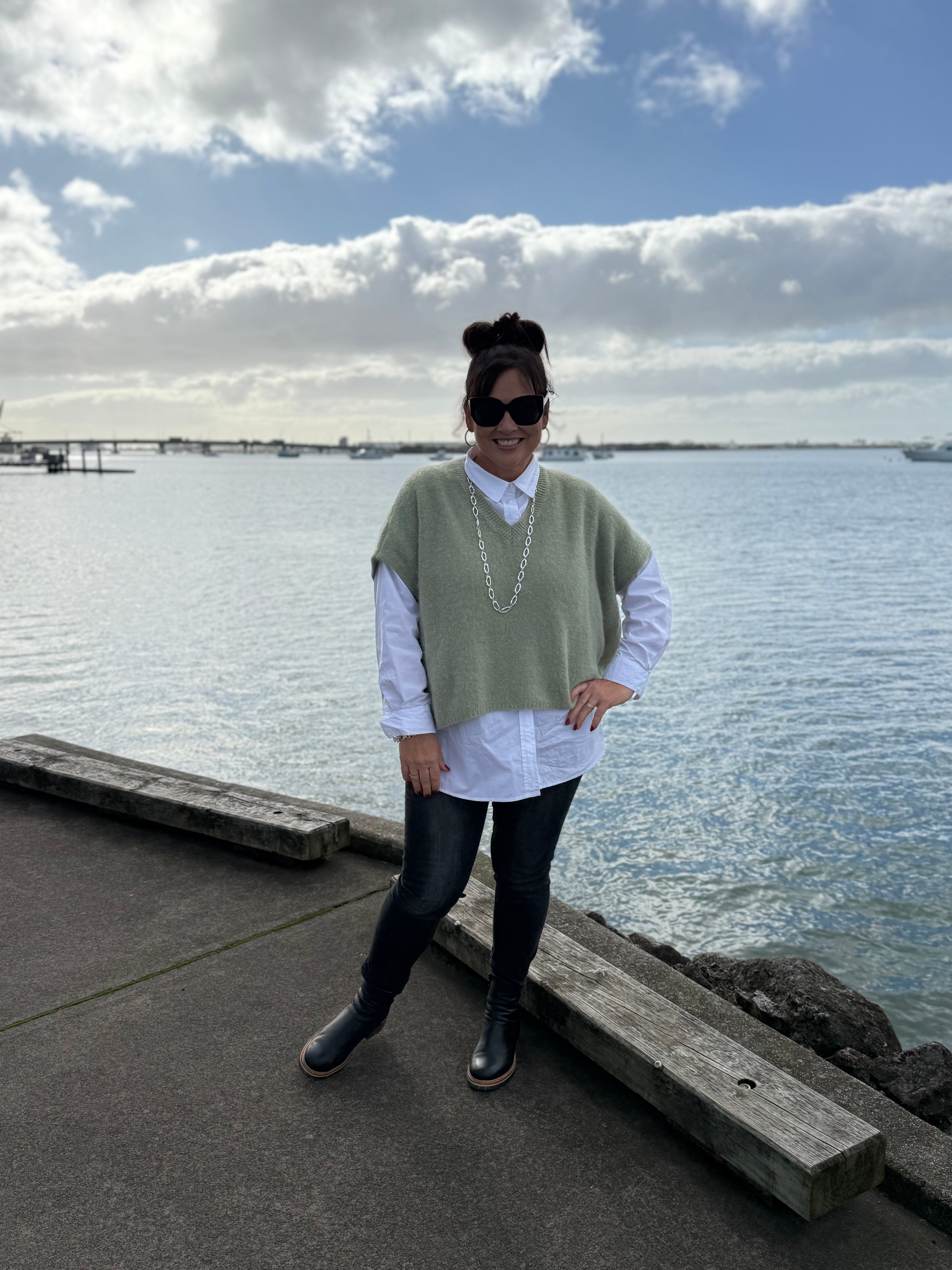 Person standing on a dock by a body of water with a scenic background